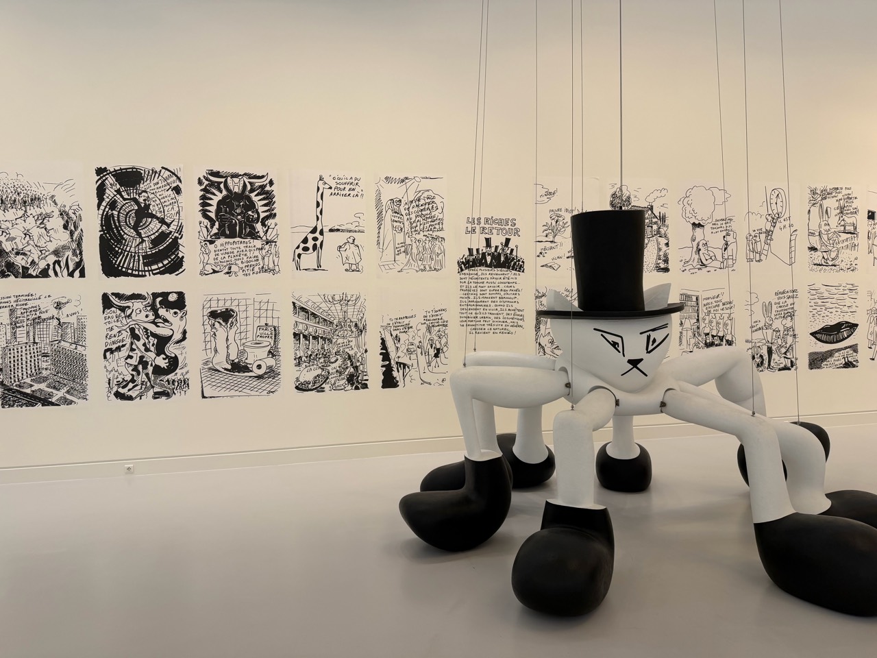 A cartoon sculpture installation and a wall of comics in a museum gallery