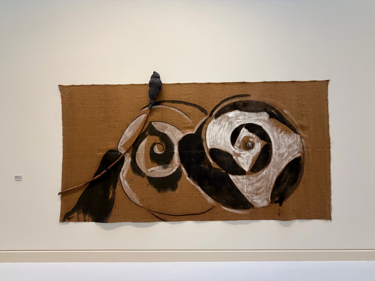 A work formed by burlap, paint, rope and an attached object
